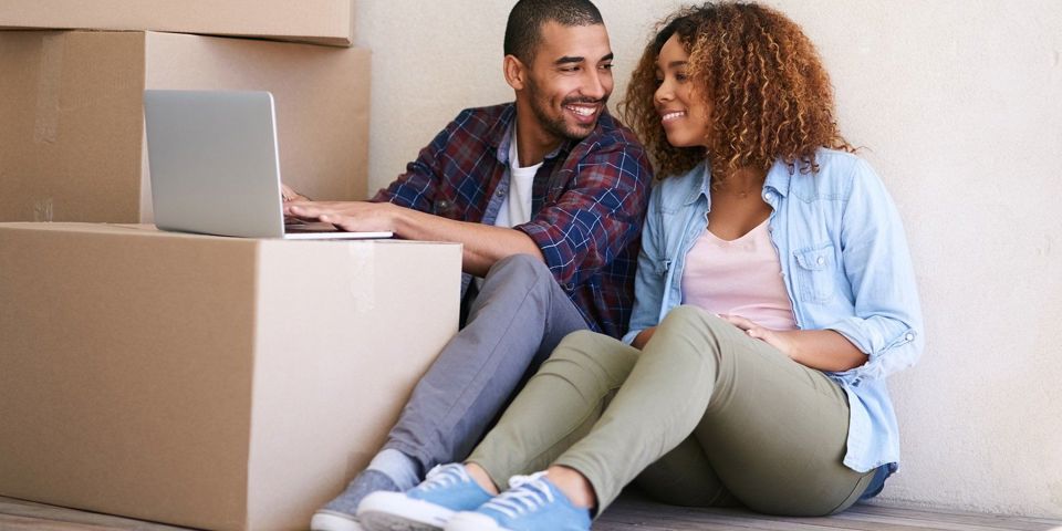 Couple sitting in new house on laptop