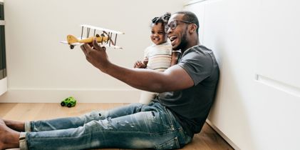 Father holding daughter with a wooden plane in his hand