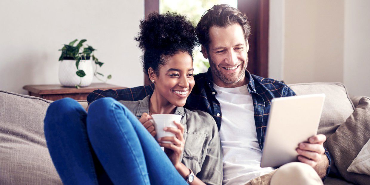 two people on couch smiling at tablet