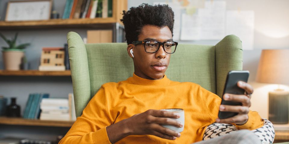 person holding cup and looking at cell