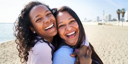 Two happy women hugging on the beach