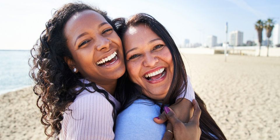 Two happy women hugging on the beach