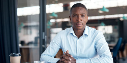 person sitting with hands clasped, looking into the camera