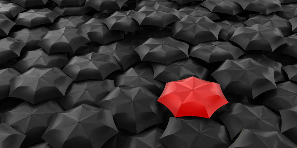 red umbrella amongst black umbrellas