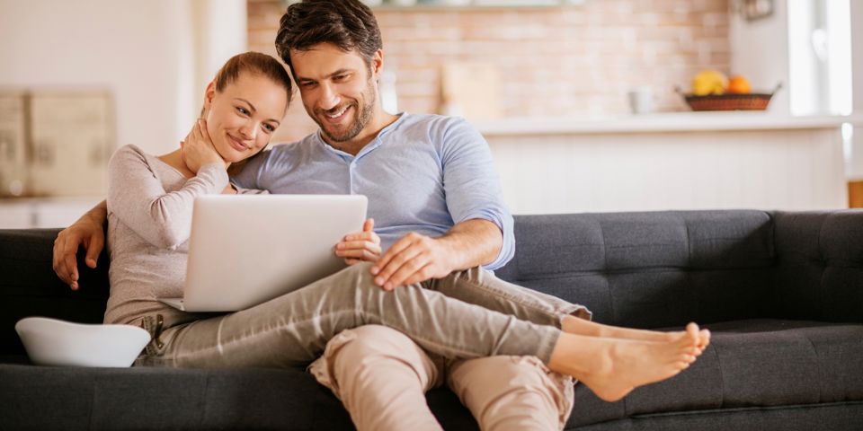 couple sitting on couch with laptop