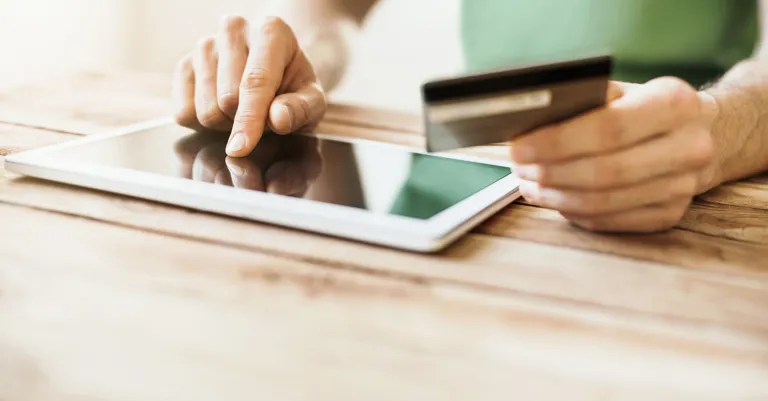 man with tablet & bank card on table